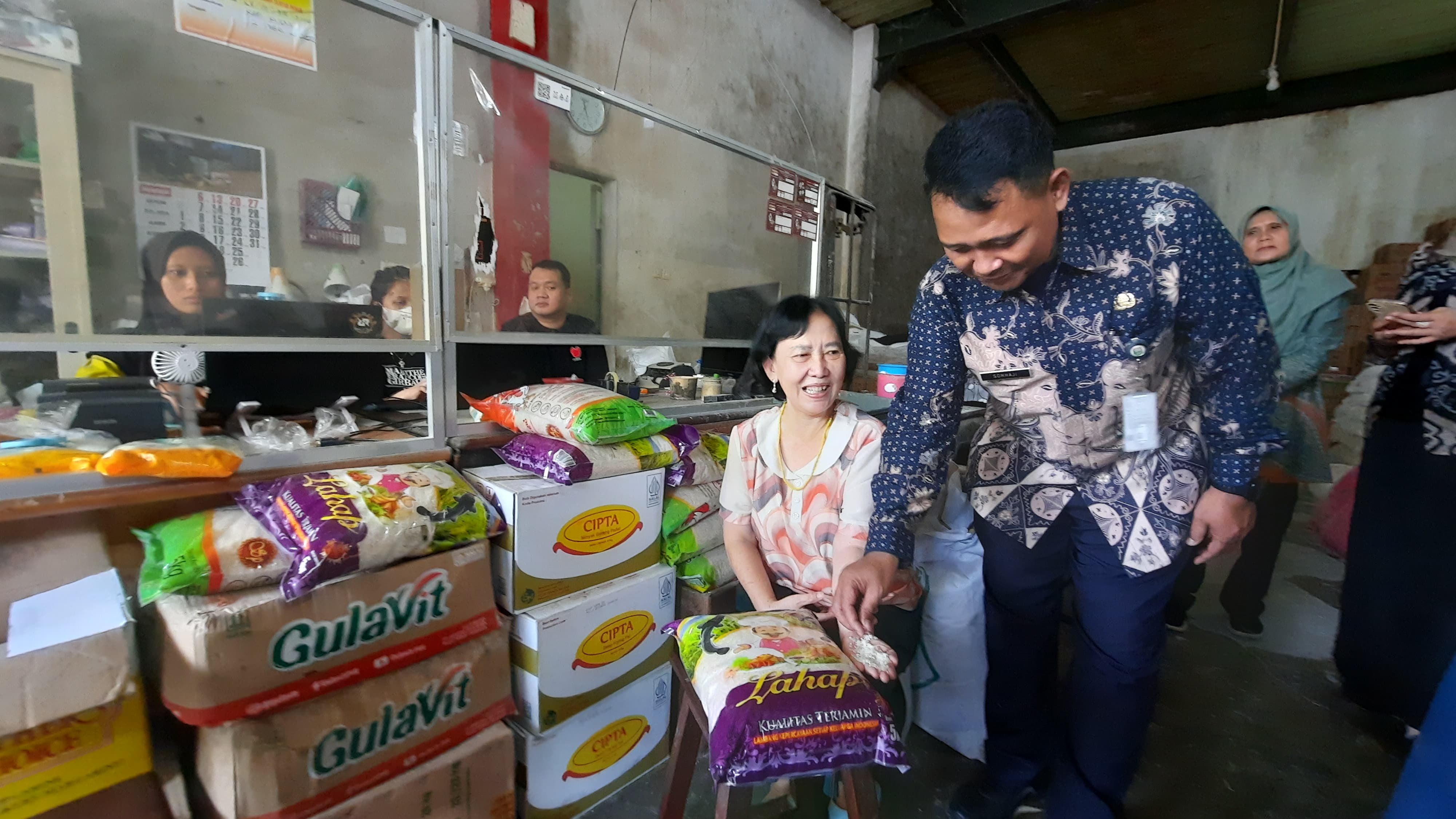 INDAH SUSANTI/RADAR KUDUS CEK BERAS: Pemilik toko Tanjung Dewi Sekti Rohmat (duduk) menunjukkan beras dari kemasan merk Lahab dan di cek langsung dari tim Dinas Perdagangan Kudus.
