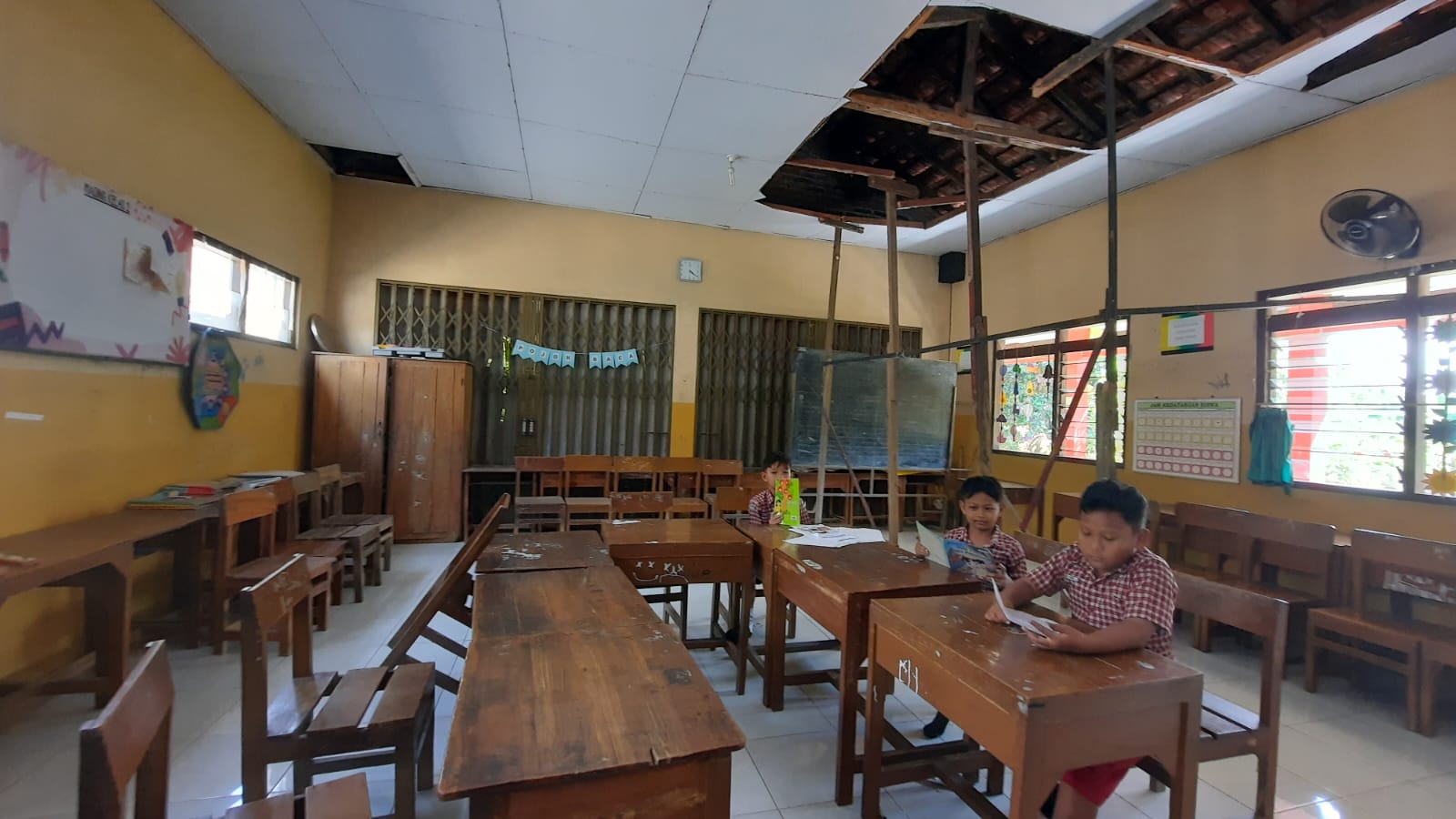 INDAH SUSANTI/RADAR KUDUS RUSAK: Siswa SD 5 Ngembalrejo belajar di kelas dengan kondisi plafon bolong dan disangga kayu.