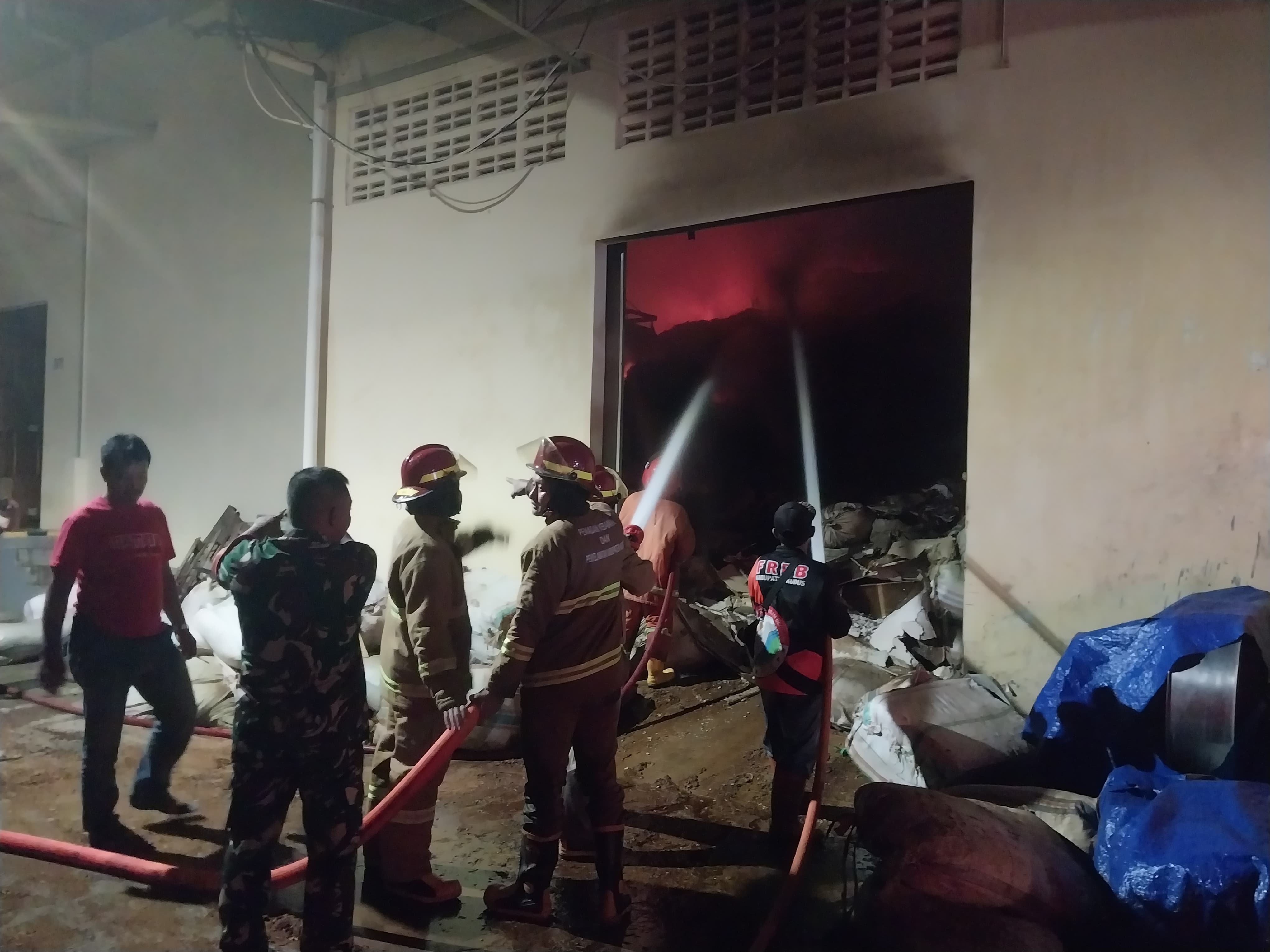 HANGUS: Proses pemadaman gudang penyimpanan ampas kopi dan klobot jagung yang terbakar, malam ini. (ANDIKA TRISNA SAPUTRA/RADAR KUDUS)