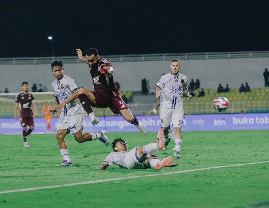 SENGIT: Wahyudi Hamisi tengah perebutkan bola liar dengan pemain PSM Makassar.