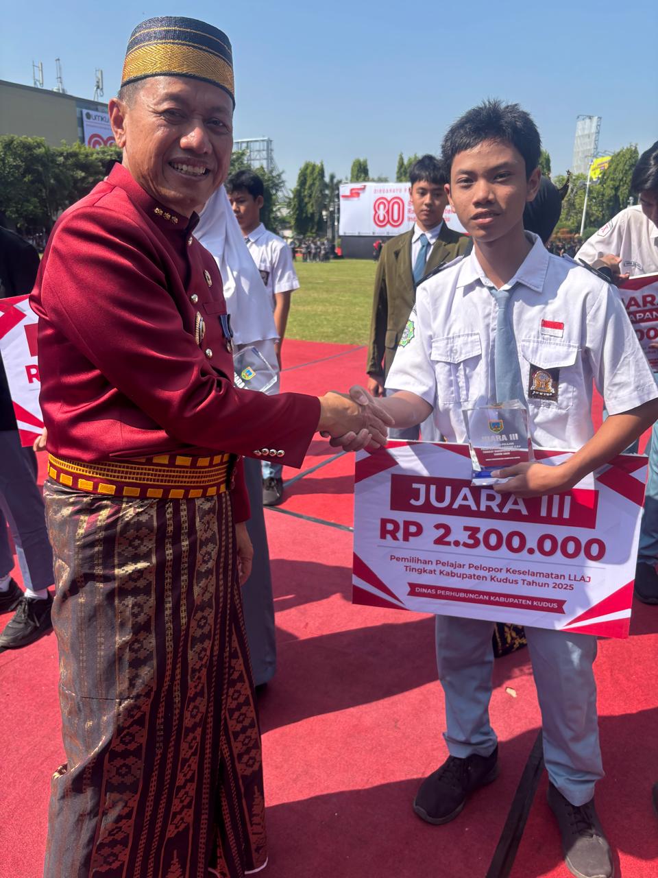 BANGGA: Bupati Kudus Sam&rsquo;ani Intakoris (kanan) menyerahkan piala pada siswa SMK Assa&rsquo;iddiyah Kudus Ilyas Ezra Laksamna juara III Pelajar Pelopor Keselamatan LLAJ di Alun-alun Simpang Tujuh Kudus.