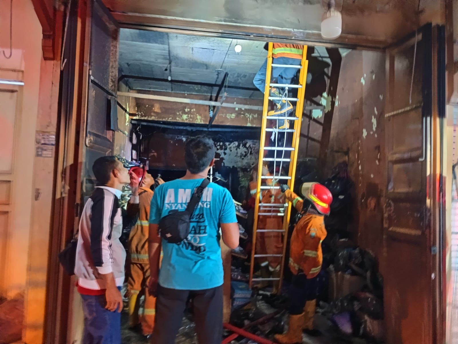 DIPADAMKAN: Petugas Damkar Rembang memadamkan toko sepatu di jalan Kartini yang terbakar (Senin, 25/8)
