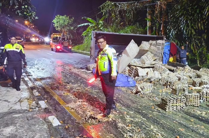 Truk oleng ke kiri, terguling, dan muatan telur yang dibawa berhamburan ke jalan.