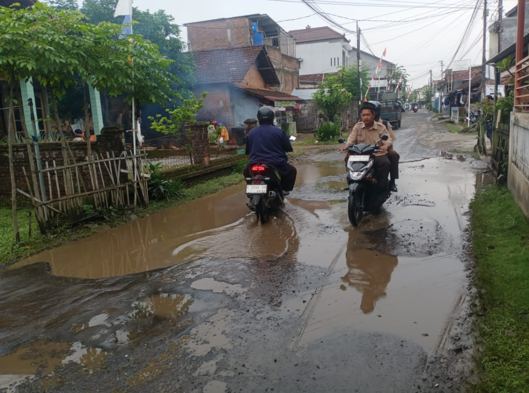 HATI-HATI: Pengendara motor mengurangi laju kendaraannya saat melintasi genangan air akibat jalan berlubang di Desa Pasuruhan Lor, Kamis (18/9). (ANDIKA TRISNA SAPUTRA/RADAR KUDUS)