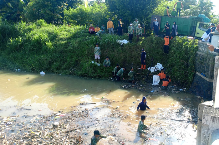 GOTONG ROYONG: Relawan membersihkan sampah yang memenuhi Sungai Piji. &nbsp;