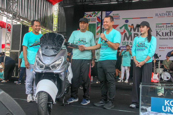 BERUNTUNG: Munarto menerima hadiah utama Mlampah Sesarengan Bupati-Wabup Kudus Menuju Kudus Sehat berupa sepeda motor Listrik Polytron.