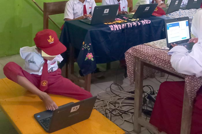 SELALU SEMANGAT: Ahmad Awaludin saat mengerjakan ANBK menggunakan laptop bersama.