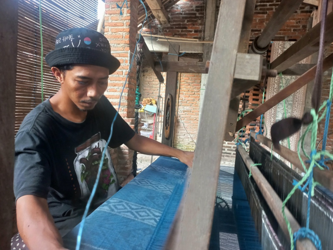 TELITI: Ahmad Karomi, tengah menenun di ruang kerjanya.