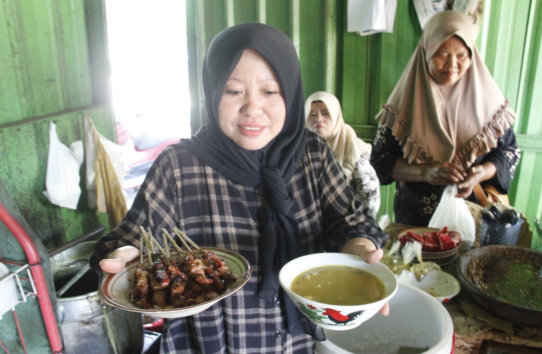 ISTIMEWA: Harti tengah menyajikan seporsi sate dan gulai untuk pembeli pada Jumat (10/10).