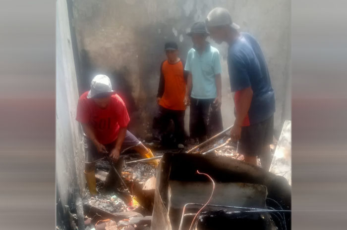 BERSIHKAN PUING: Kades Ngasmin (pakai helm) bersama warga ikut kerja bakti membersihkan puing bangunan bekas kebakaran.