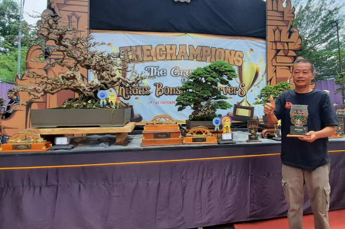 JUARA: Gunawan menunjukkan piala disamping bonsai Santigi yang menjadi juara kontes bonsai nasional di Balai Jagong Kudus.