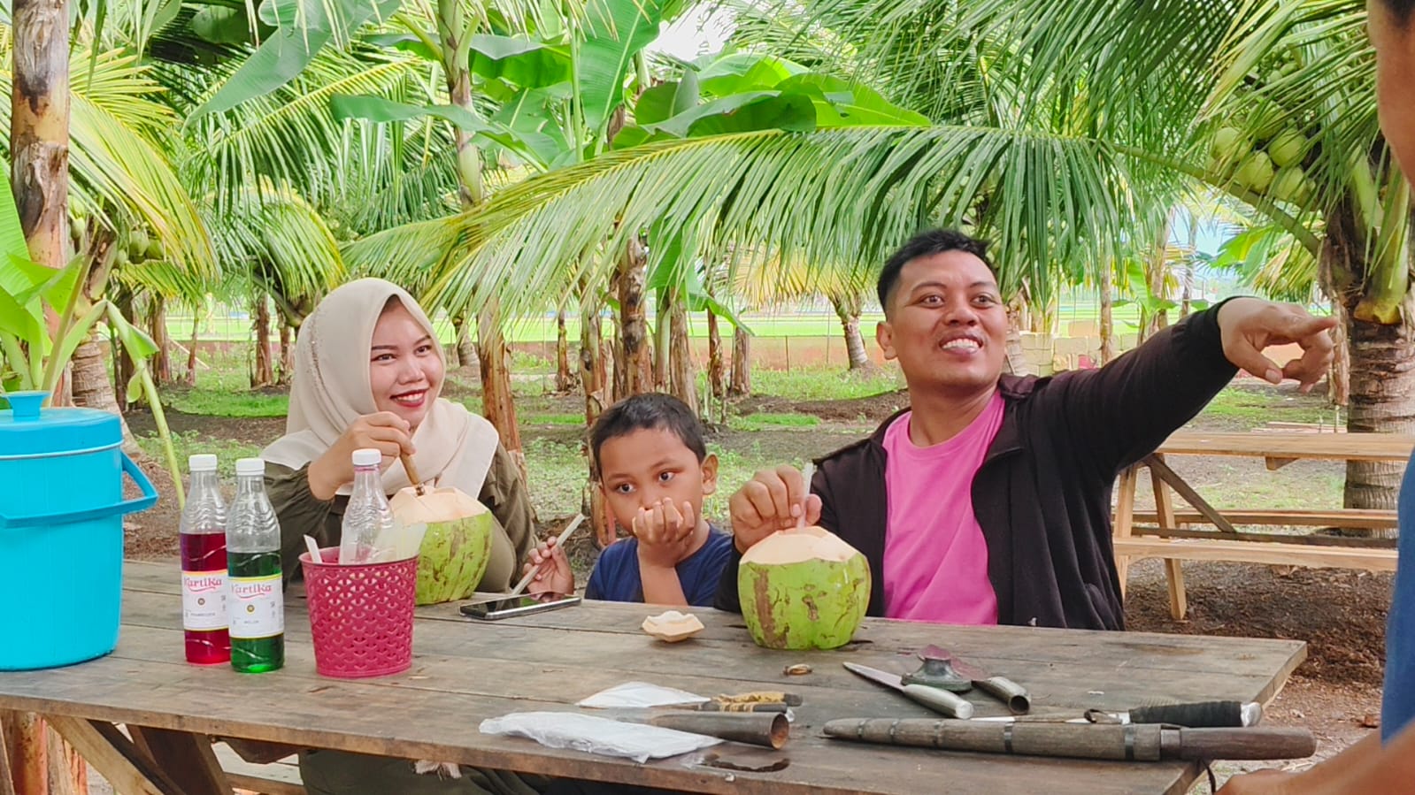 SEGAR &ndash; Pengunjung bersama anak serta istrinya sedang menikmati air kelapa muda di kebun Kelapa di Desa Wolo, Kecamatan Penawangan.