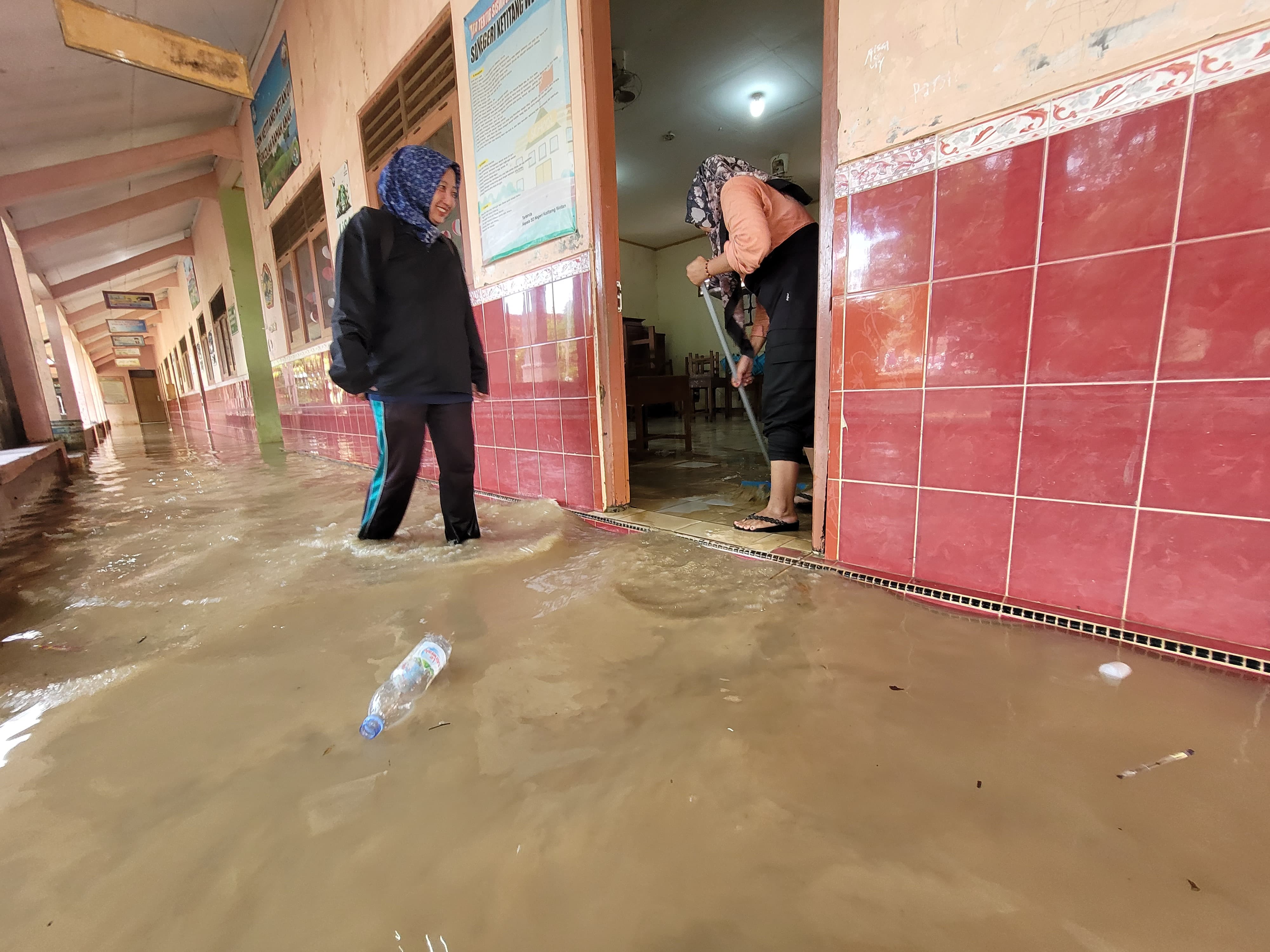 TERGENANG: Pihak sekolah membersihkan salah satu ruang kelasnya pada Selasa (28/10).