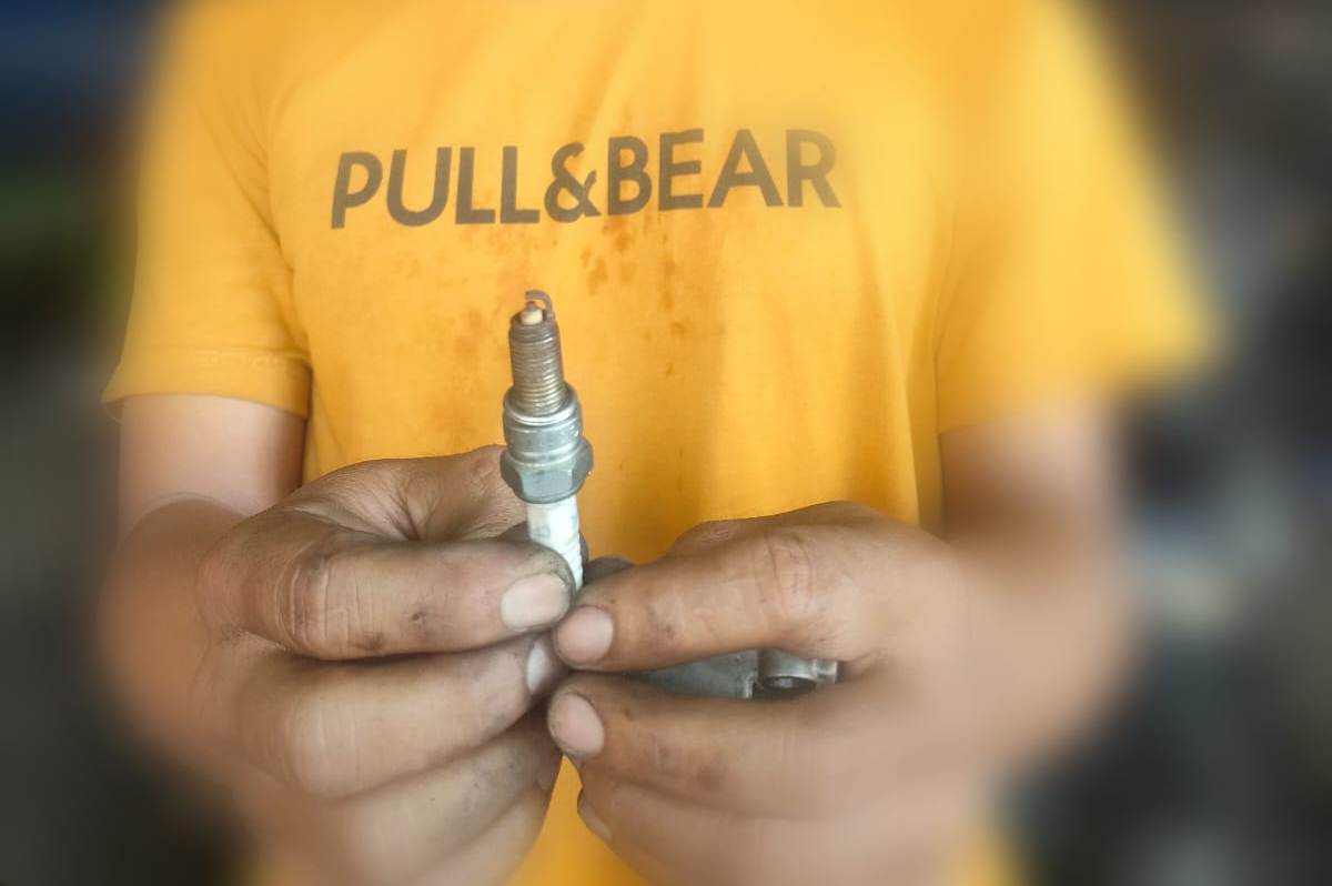 GANTI BUSI: Seorang mekanik menujukan busi motor yang sudah tidak berfungsi karena diduga bahan bakar yang digunakan bercampur air.