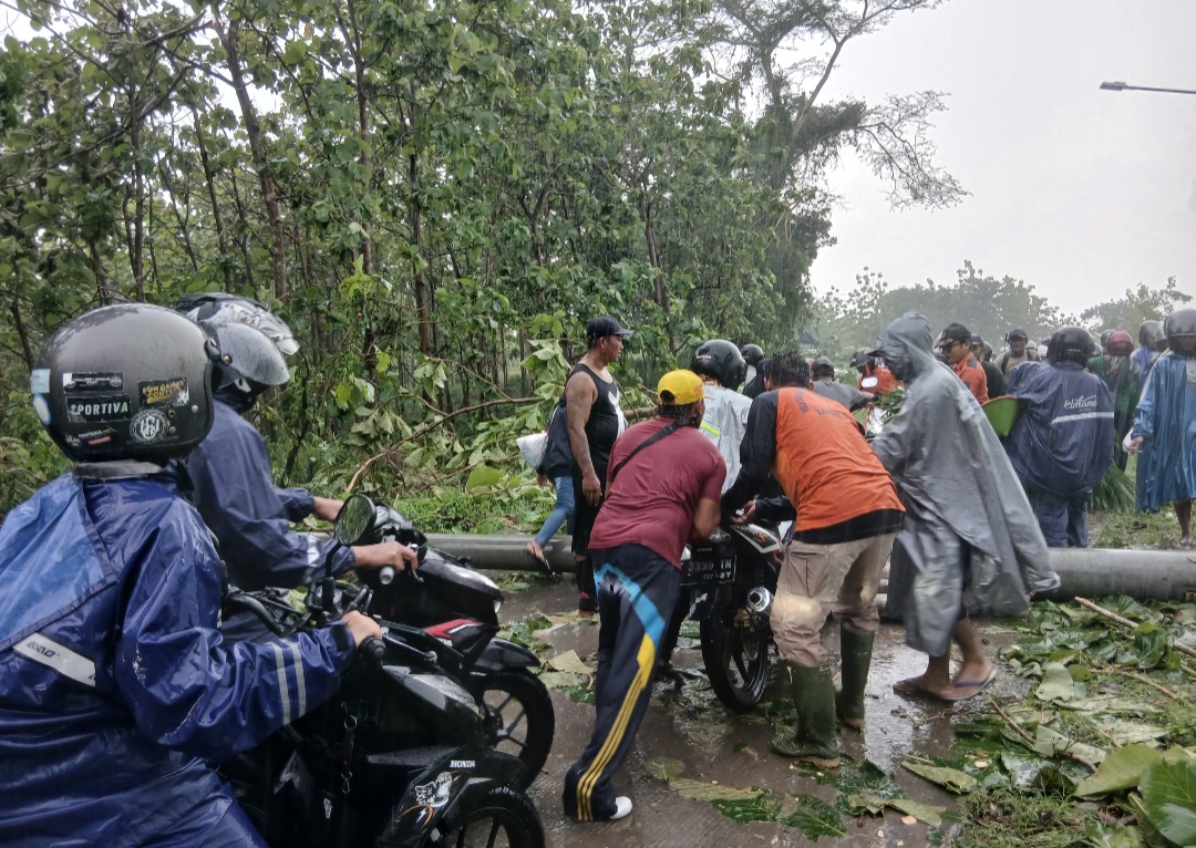 HATI-HATI: Pengendara saat gotong-royong menaikkan motor melintasi tiang listrik di Jalan Blora-Randublatung.