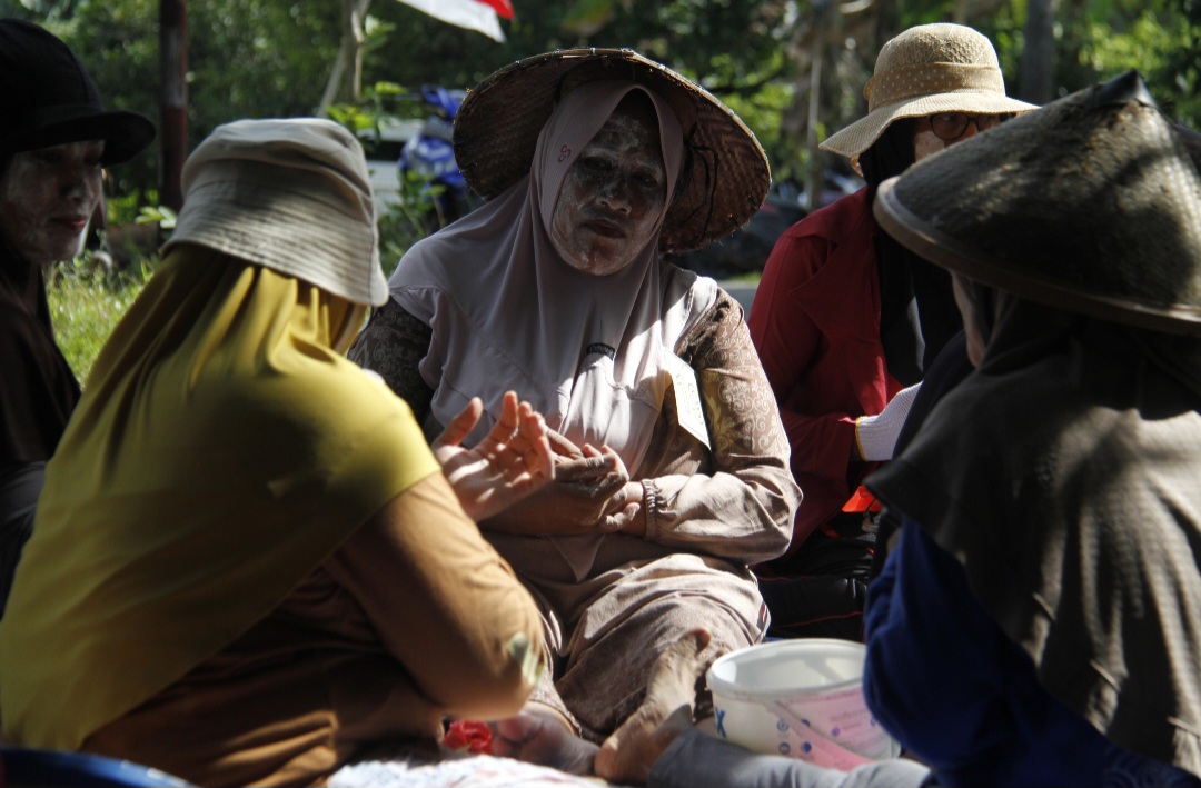KHIDMAT: Peserta tengah berdoa dan menggunakan pupuran (bedak) racikan sebelum berangkat ke terusan.
