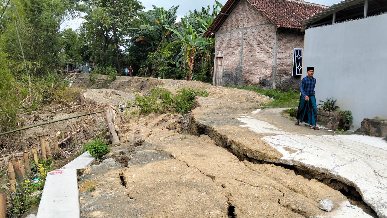 LONGSOR: Warga saat melintasi jalan yang longsor di Kuripan Kecamatan Purwodadi.