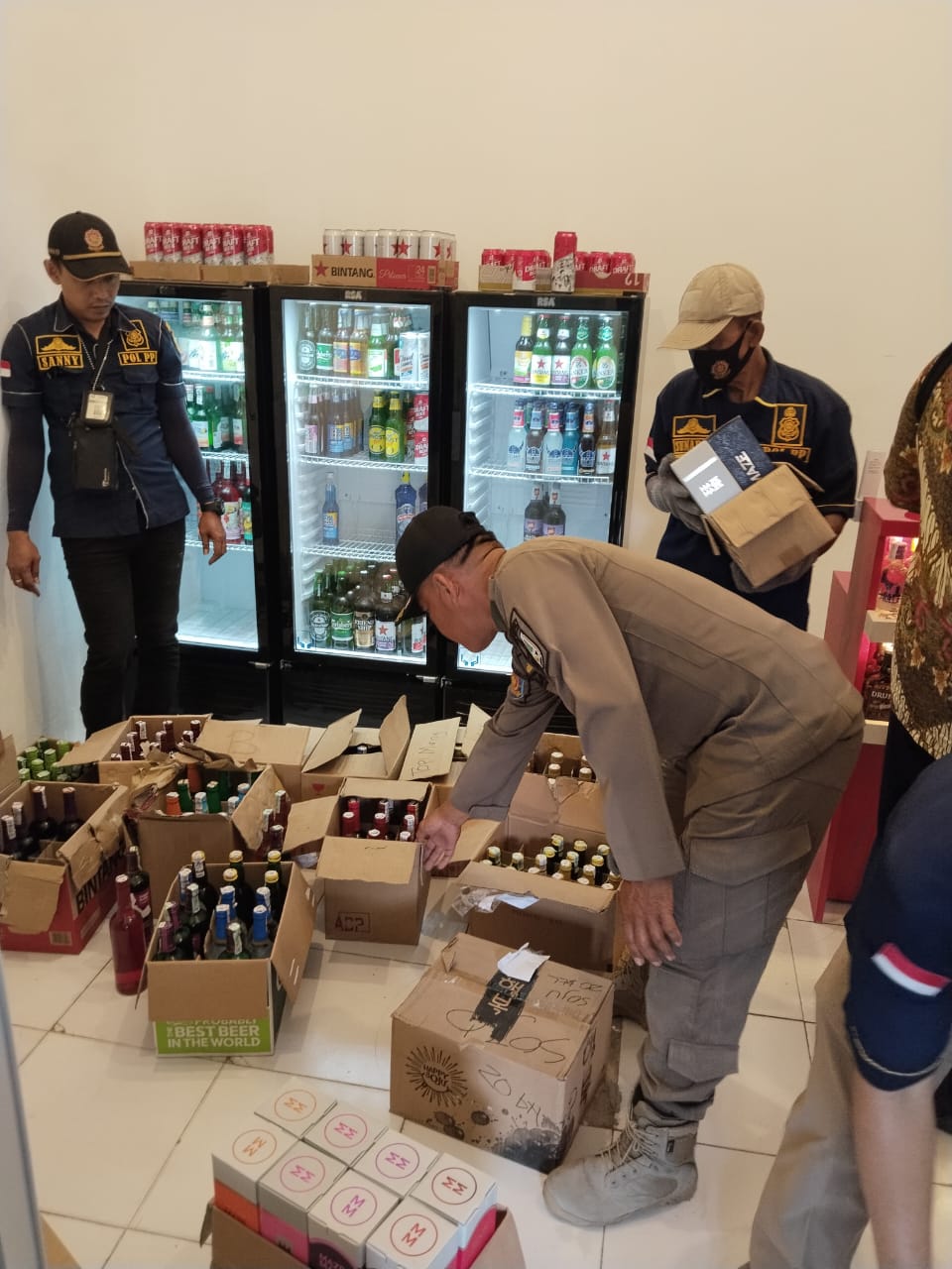 HITUNG BOTOL: Petugas Satpol PP Rembang menghitung botol miras berbagai merek hasil penggerebekan di Jalan Pemuda, Rembang, beberapa hari lalu.