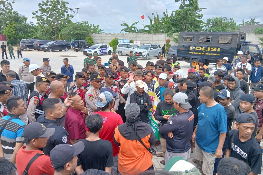 SEMANGAT: Warga Desa Jiken, Kecamatan Jiken saat membawa spanduk tuntutan di hadapan kepolisian yang mengamankan pabrik.