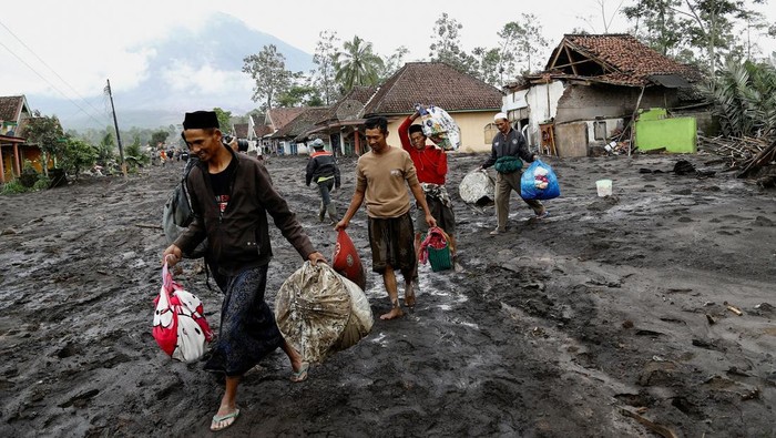 Warga membawa barang berharga dari rumah mereka di daerah yang terdampak erupsi Gunung Semeru, di Desa Supiturang, Lumajang, Jawa Timur, Kamis (20/11/2025).