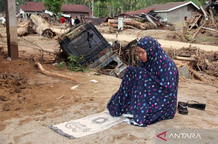 Warga menunaikan shalat di area rumah yang rusak akibat banjir bandang di Desa Aek Garoga, Kecamatan Batang Toru, Kabupaten Tapanuli Selatan, Sumatera Utara, Minggu (30/11/2025).