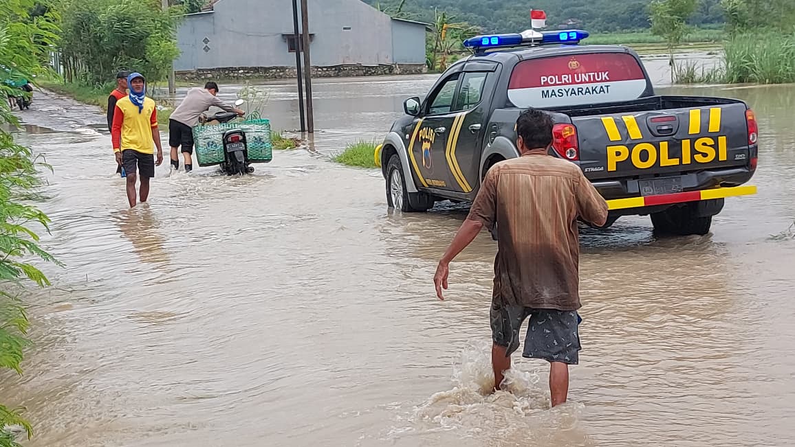 BANTU WARGA: Anggota Polsek Lasem membantu menyeberangkan sepeda motor warga yang melintas di Jalan Desa Sendangasri kemari.