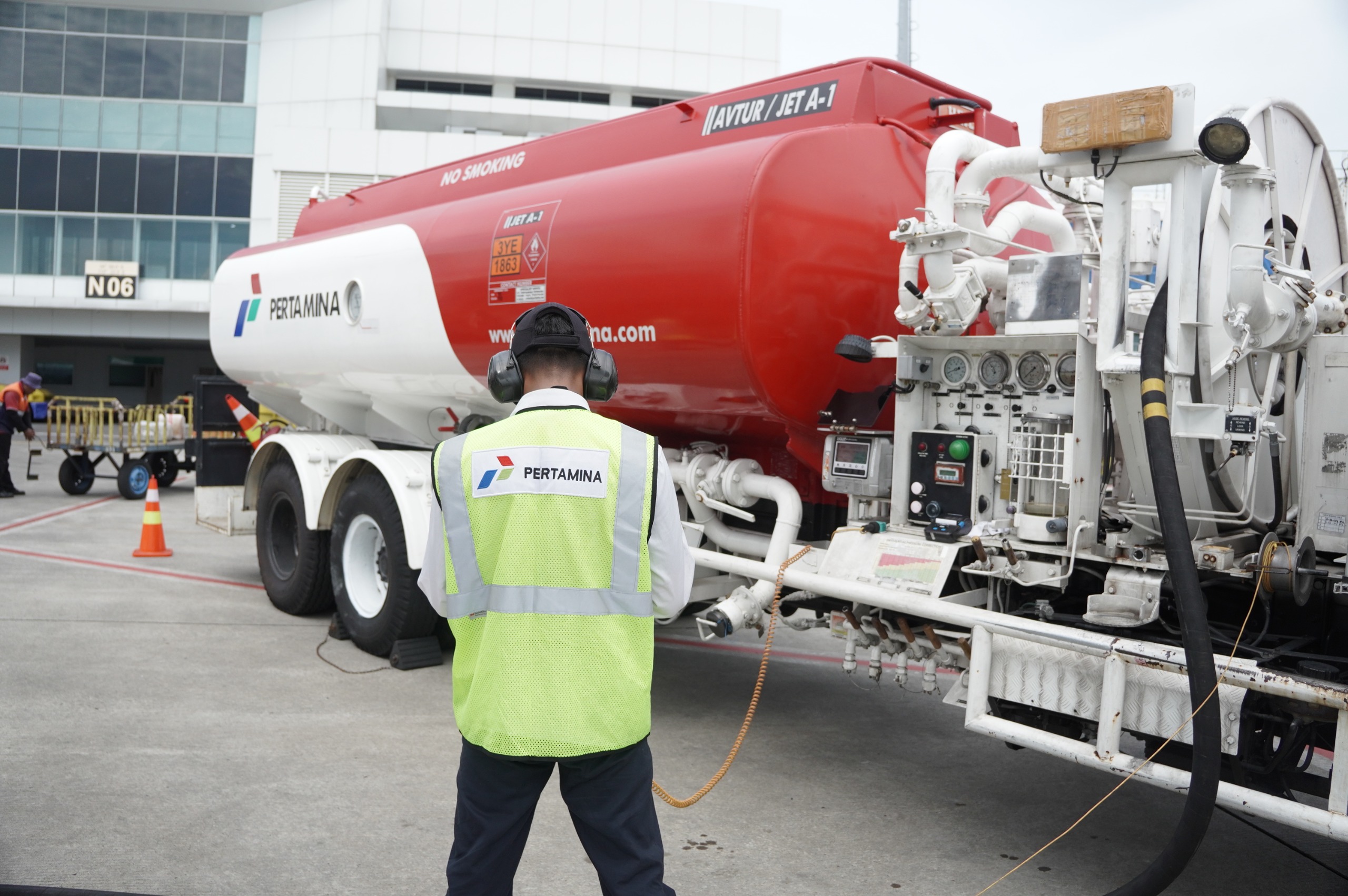 Ilustrasi pegawai Pertamina mengecek tangki truk bahan bakar