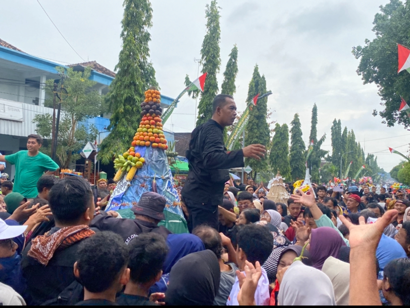 REBUTAN: Warga berebut gunungan yang berisi buah, sayur dan hasil bumi di sepanjang Jalan Pemuda Blora.
