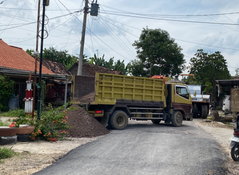 BERPROSES: Beberapa truk berisi material menurunkan pasir untuk proyek peningkatan jalan Plosorejo - Sembongin.