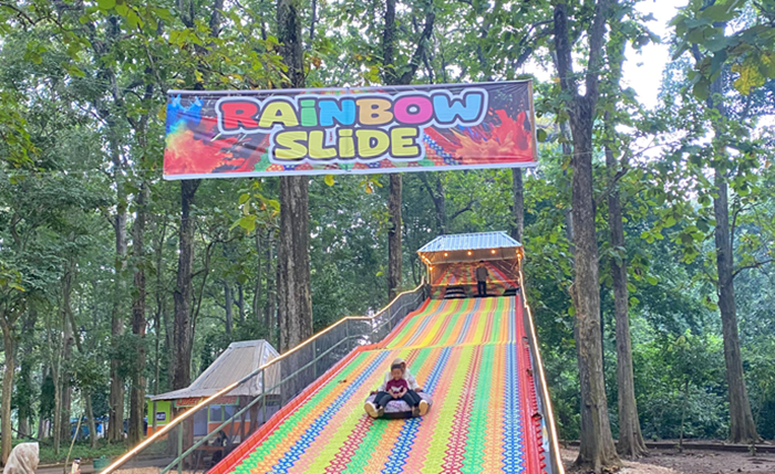 Wahana Rainbow Slide di Goa Terawang EcoPark, Blora, menawarkan sensasi meluncur seru di lintasan warna-warni yang membelah kawasan hutan jati.