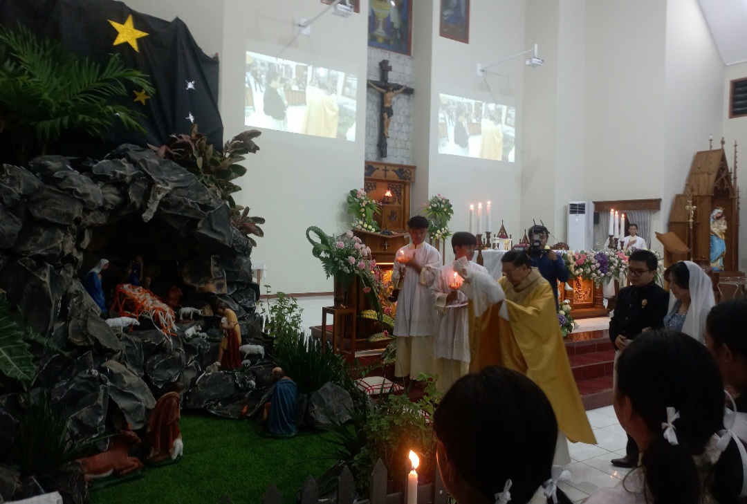 KHIDMAT: Romo Antonius Gunardi Prayitna MSF meletakkan bayi Yesus usai dilakukan perarakan pada Rabu (24/12) malam.