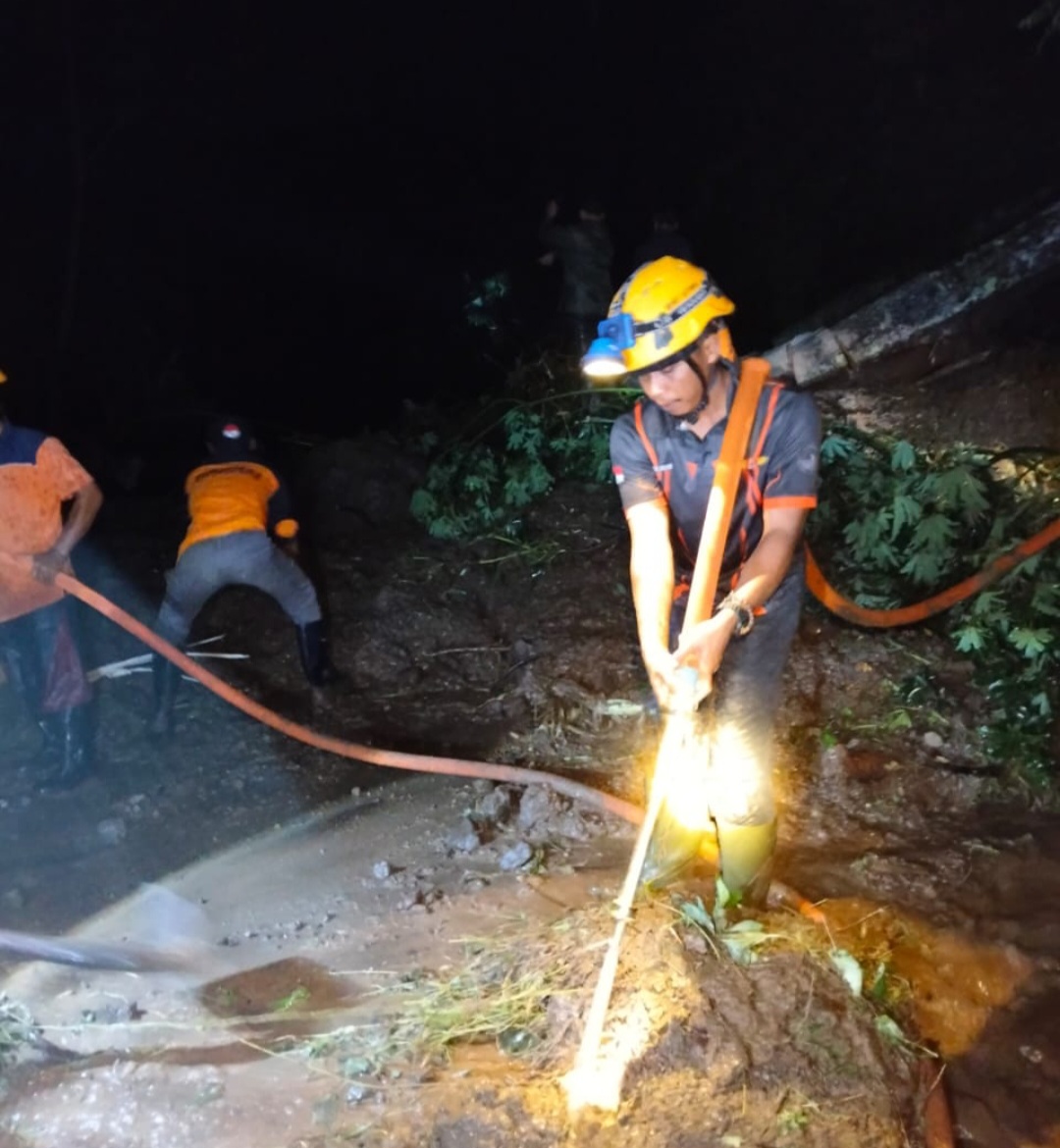 BERJIBAKU: Petugas tengah membersihkan material lumpur yang menutupi badan jalan Damarwulan-Tempur.