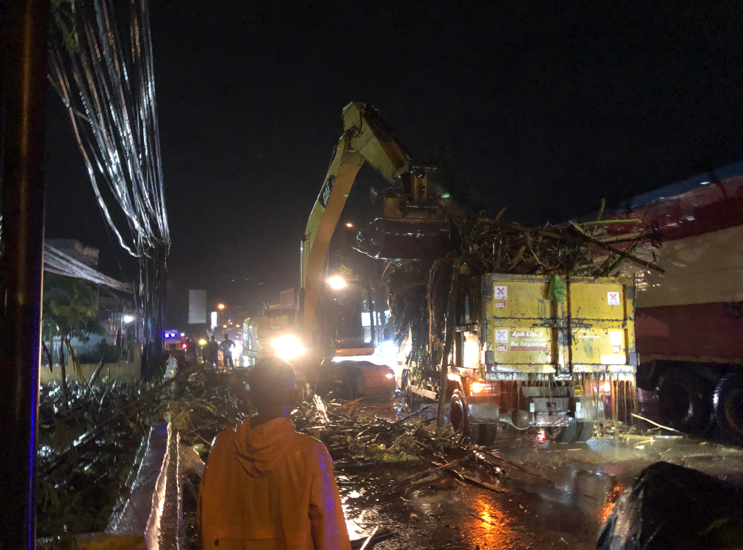 BERSIHKAN: Alat berat sedang dioperasikan untuk membersihkan batang bambu yang menyumbat, Jumat (9/1) malam. (HAMMAD MAGANG RADAR KUDUS)