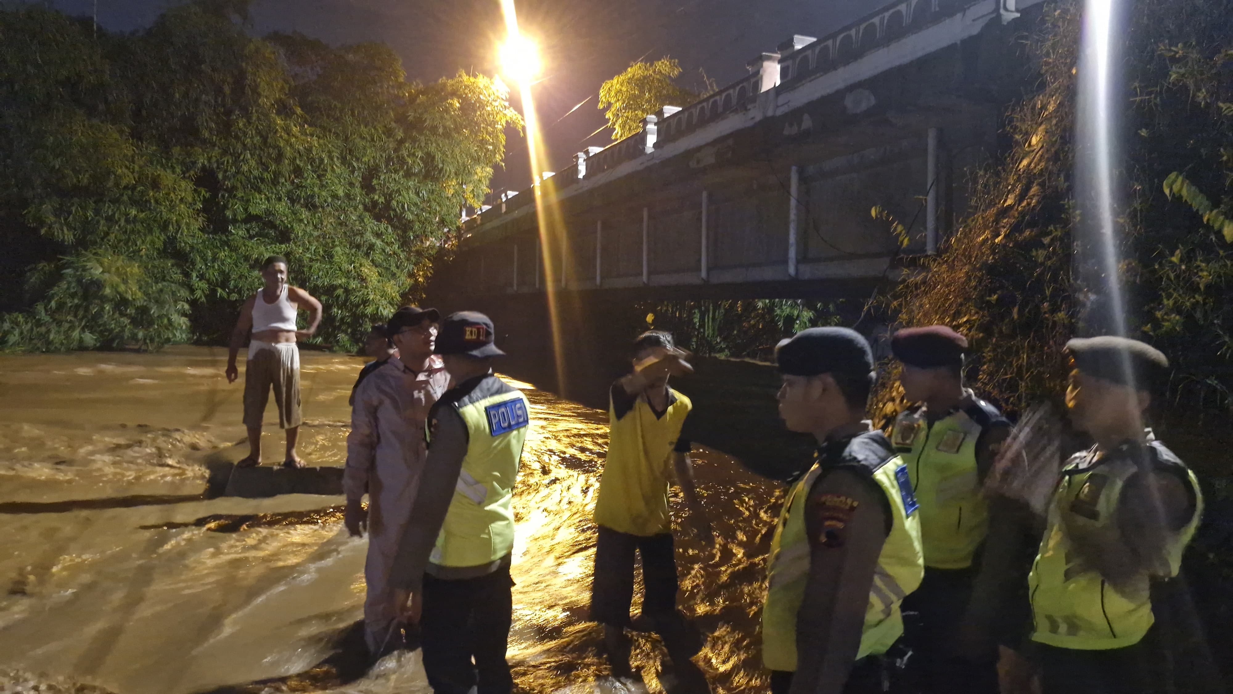 EVAKUASI: Polisi berada di dekat wilayah yang terkena banjir di Desa Singocandi.