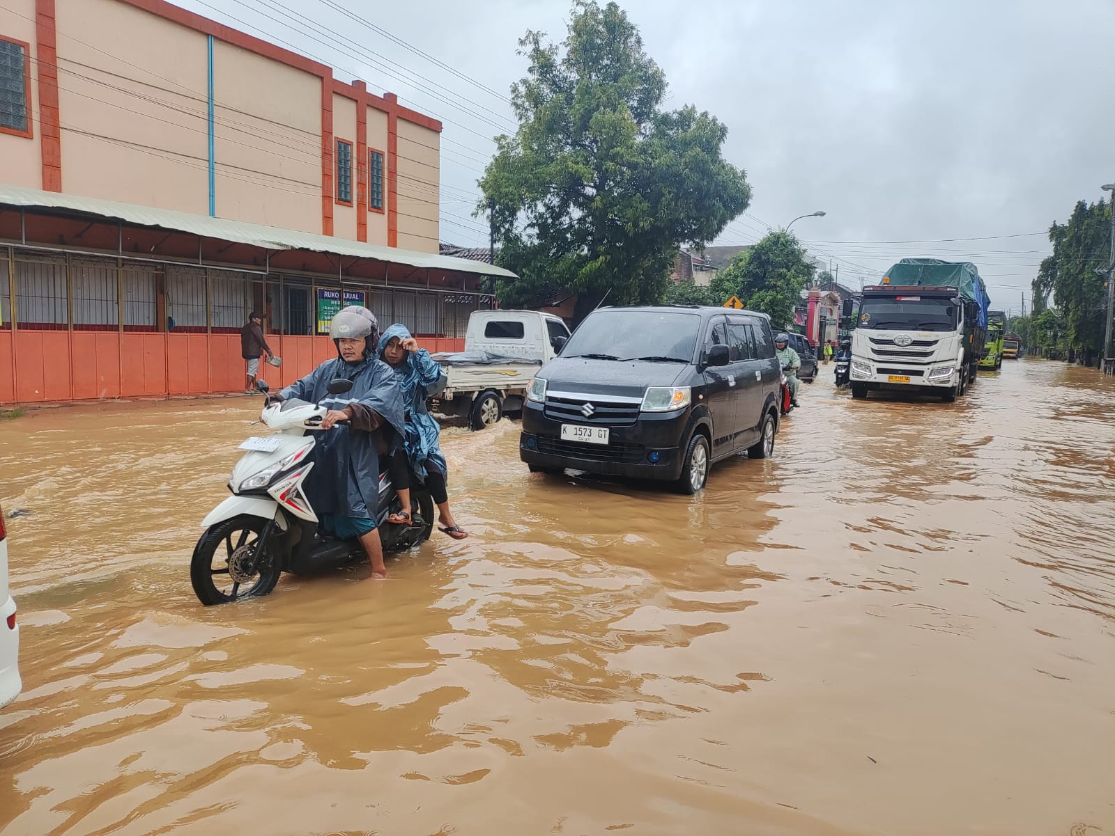 TERSENDAT: Warga melintas di Jalan Pantura Kudus-Pati turut Desa Ngembalrejo yang terendam banjir.