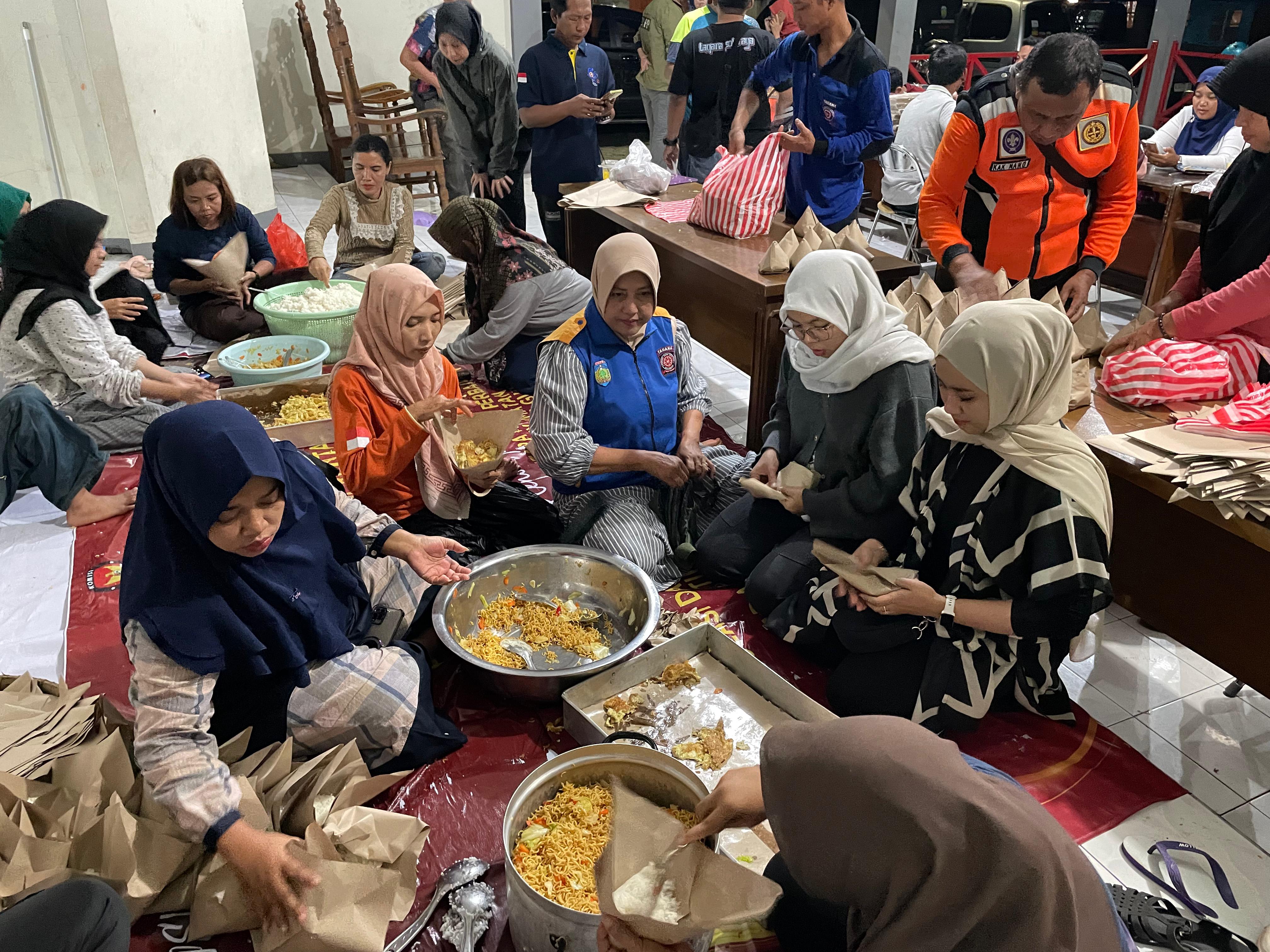 PENUHI KEBUTUHAN: Para relawan tengah menyiapkan nasi bungkus bagi para warga yang terdampak banjir pada Selasa (13/1) malam di Kantor Kecamatan Kalinyamatan.