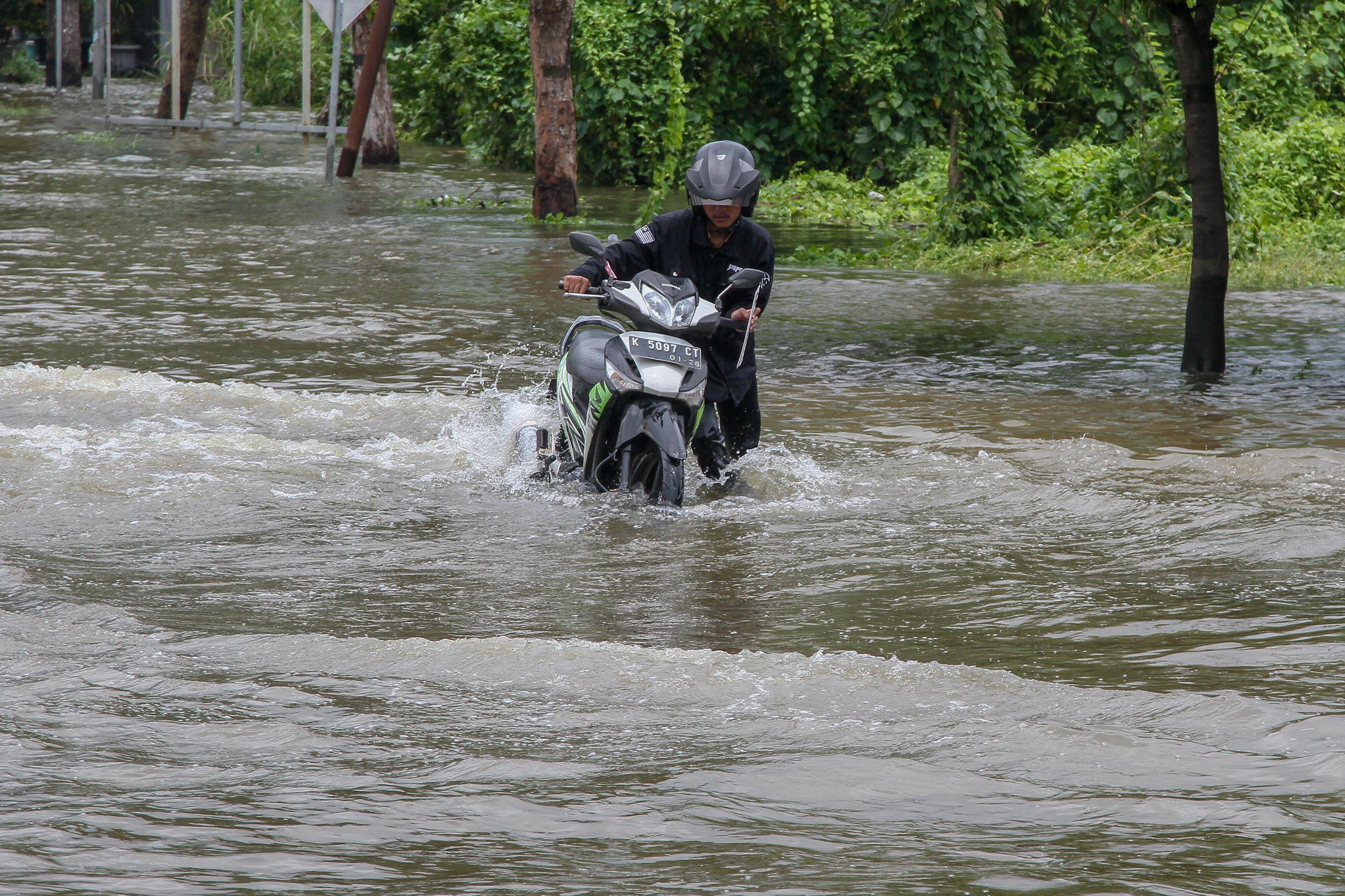 NEKAT MELINTAS: Warga melintas di Jalan Kudus-Purwodadi yang terendam banjir.