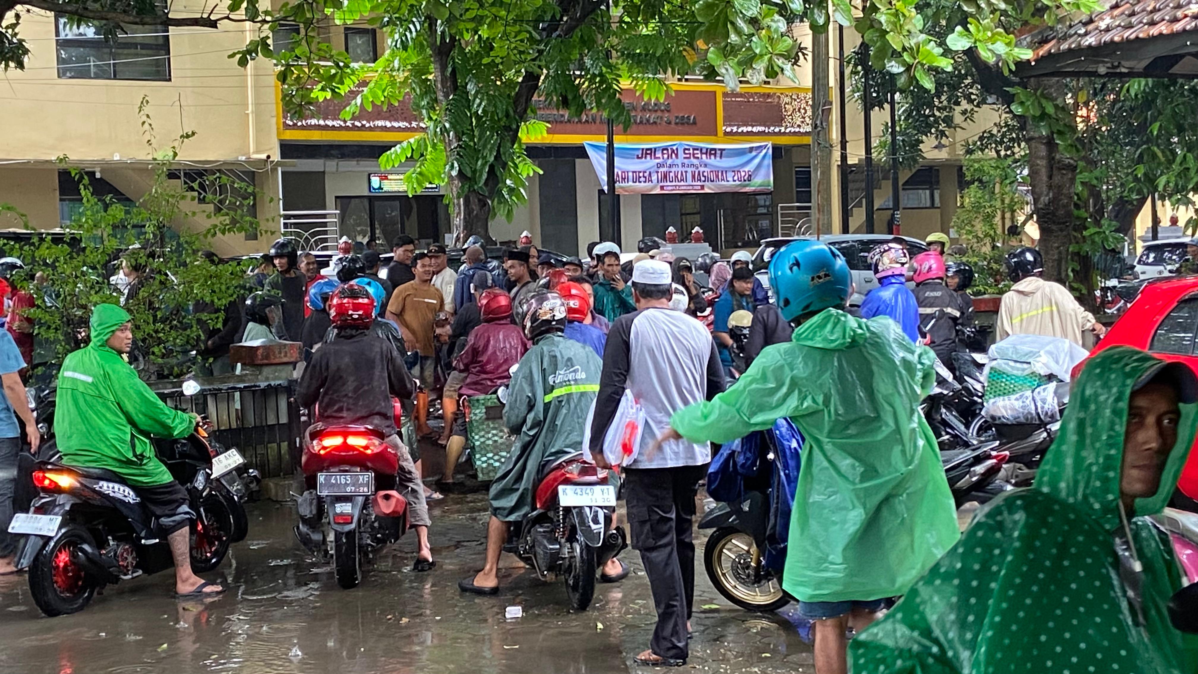 HUJAN: Warga beraktivitas saat kondisi hujan pakai jas hujan