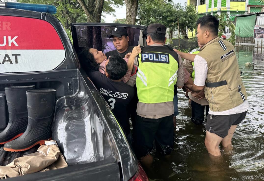 GERAK CEPAT: Polisi berusaha mengevakuasi warga yang terkena stroke di tengah banjir