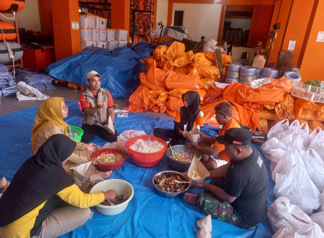 RIBUAN PORSI: Relawan cepak-cepak dan membungkus makanan untuk warga terdampak banjir.