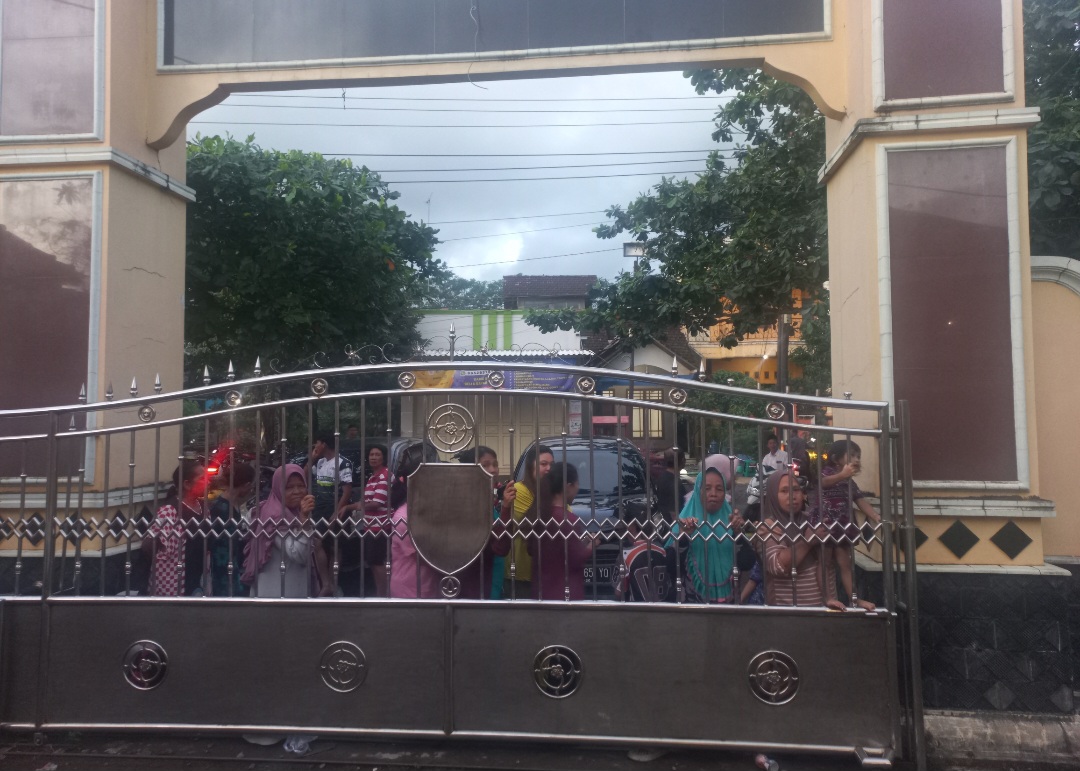 PENASARAN: Ratusan warga turut menyaksikan proses pemeriksaan terhadap para saksi dari luar pagar Balai Desa Tubanan pada Jumat (6/2).