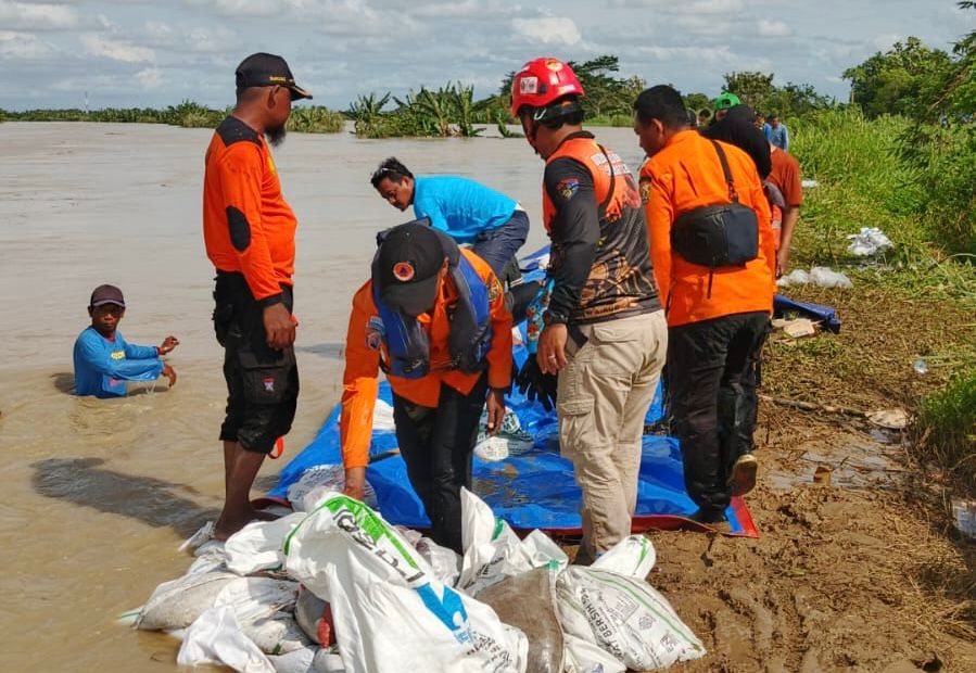 TINGGIKAN TANGGUL - Petugas gabungan memperkuat tanggul sungai menggunakan kantong berisi pasir di Desa Gubug, Kecamatan Gubug, Kabupaten Grobogan, Jawa Tengah, Senin (16/2)