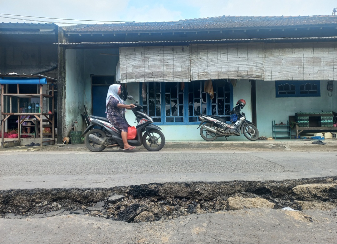 TANAH LABIL: Warga tengah melintas di area jalan yang amblas pada Kamis (19/2).