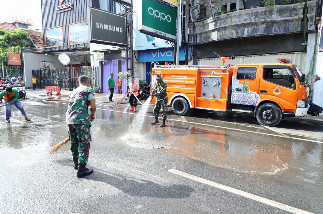BERSIH-BERSIH: Mobil damkar menyemprotkan air untuk membersihkan bekas minyak di Jalan Sunan Kudus, Jumat (20/2). (DINAS KOMINFO KUDUS UNTUK RADAR KUDUS)