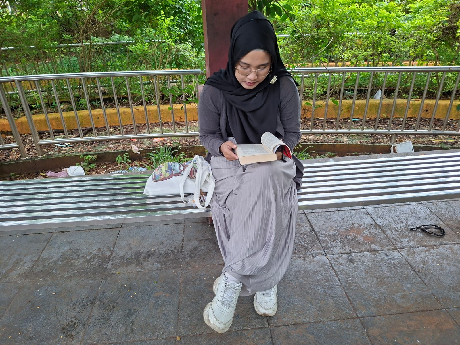 NGABUBURIT: Rofida Ilya menunggu waktu berbuka dengan membaca buku di Balai Jagong Kudus, Jumat (20/2). (ANDIKA TRISNA SAPUTRA/RADAR KUDUS)