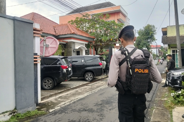 BERIDIRI: Polisi menjaga kediaman Kepala DPUTR Pati Riyoso di Desa Ngarus, Pati pada Jumat (27/2). 