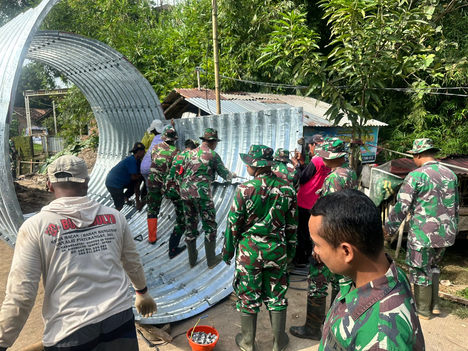 GOTONG ROYONG: Anggota Kodim 0722/Kuds bersama warga membangun jembatan armco di Desa Pedawang