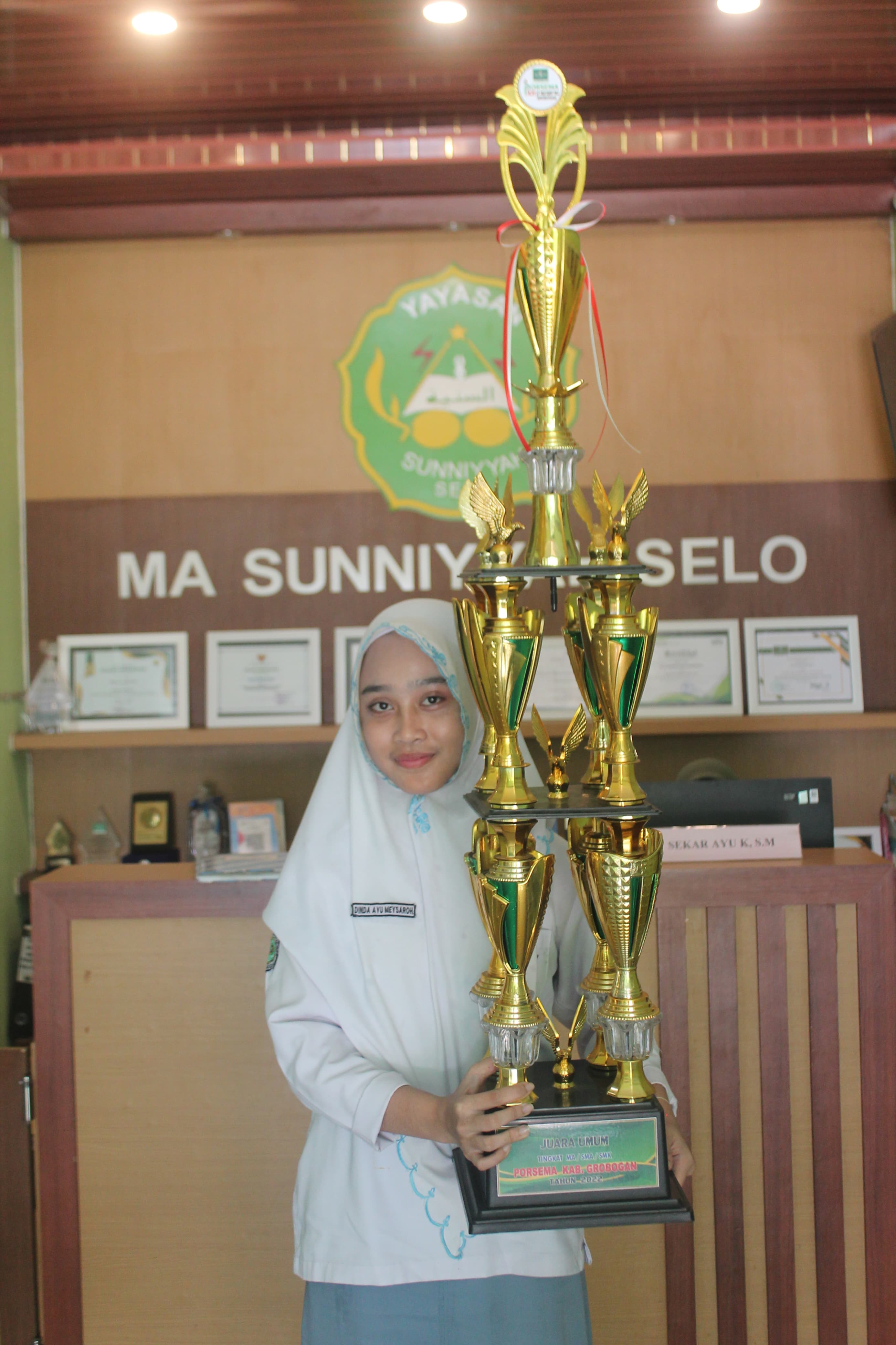 MANTAP: Salah satu siswa MA Sunniyyah Selo saat menunjukkan piala Porsema Kabupaten Grobogan.