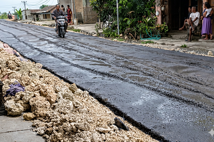 LEWAT: Agus Sutrisno atau lebih dikenal Agus Palon saat mengendarai motor di jalan cor yang masih basah.  
