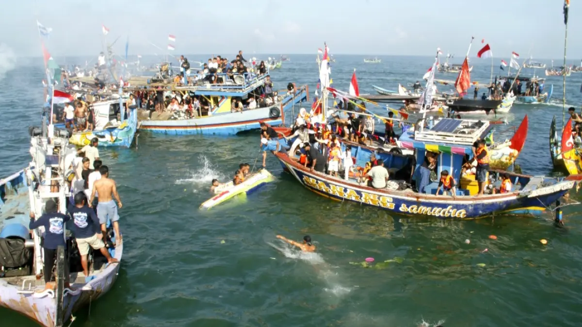 HARMONI: Masyarakat pesisir dan nelayan memperebutkan kapal larungan kepala kerbau di tengah laut pada Sabtu (28/3). (FIKRI THOHARUDIN/RADAR KUDUS)